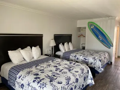 a hotel room with two beds and a surfboard on the wall at Ocean Surf Inn & Suites in Huntington Beach