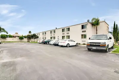 a white van parked in a parking lot in front of a building at Motel 6-Carson, CA in Carson