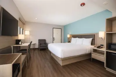 a hotel room with a large white bed and a television at Travelodge by Wyndham LAX in El Segundo