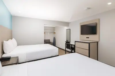 a hotel room with two beds and a flat screen tv at Travelodge by Wyndham LAX in El Segundo