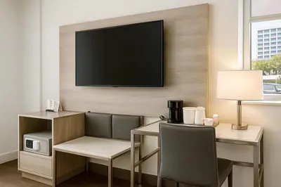 a room with a desk and a television on a wall at Travelodge by Wyndham LAX in El Segundo