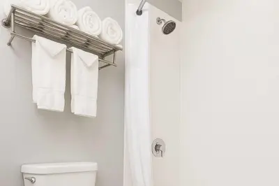 a bathroom with a toilet and a shower with towels at Travelodge by Wyndham LAX in El Segundo