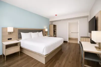 a bedroom with a large white bed and a desk at Travelodge by Wyndham LAX in El Segundo