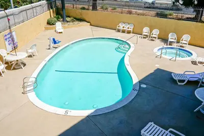 an empty swimming pool with chairs and tables at Ramada by Wyndham Ontario Airport & Convention Center in Ontario