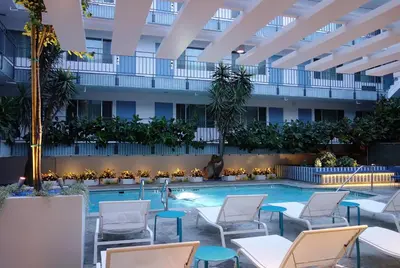 a hotel pool with chairs and a building at The Beverly Laurel Hotel at West Hollywood in Los Angeles