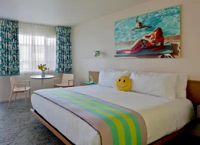 a bedroom with a large bed with a painting on the wall at The Beverly Laurel Hotel at West Hollywood in Los Angeles