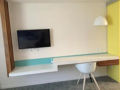 a room with a desk with a tv on a wall at The Beverly Laurel Hotel at West Hollywood in Los Angeles