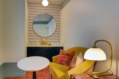 a living room with a yellow couch and a mirror at The Hollywood Franklin Hotel near Universal Studios in Los Angeles