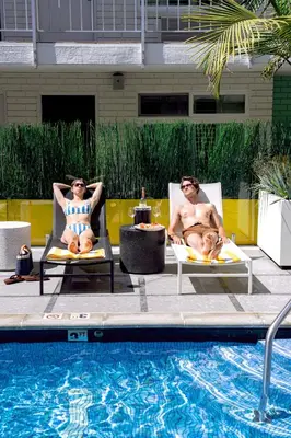 two men sitting in lawn chairs next to a swimming pool at The Hollywood Franklin Hotel near Universal Studios in Los Angeles