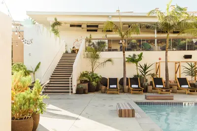a resort with a swimming pool with chairs and a staircase at Hotel June West LA, a Member of Design Hotels in Los Angeles