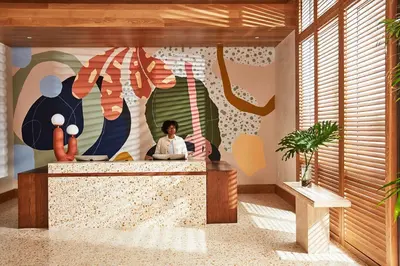 a man sitting at a desk in a room with a mural at Hotel June West LA, a Member of Design Hotels in Los Angeles