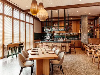 a restaurant with wooden tables and chairs and a bar at Hotel June West LA, a Member of Design Hotels in Los Angeles