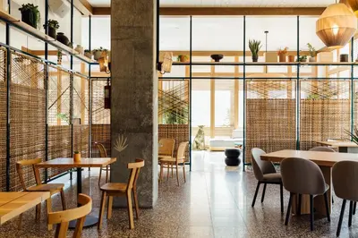 a restaurant with tables and chairs and large windows at Hotel June West LA, a Member of Design Hotels in Los Angeles
