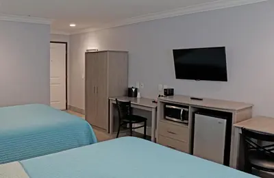 a hotel room with two beds and a flat screen tv at Surf City Inn in Huntington Beach