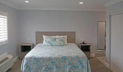 a bedroom with a large bed and two tables at Surf City Inn in Huntington Beach