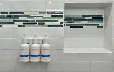 a bathroom with two white bottles on a tile wall at The Pacific Inn in Seal Beach