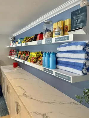 a kitchen pantry with white shelves and towels at The Pacific Inn in Seal Beach