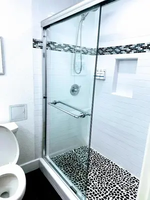 a bathroom with a glass shower with a toilet at The Pacific Inn in Seal Beach