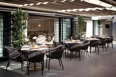 a dining room with tables and chairs and plants at Luxe Sunset Boulevard Hotel in Los Angeles