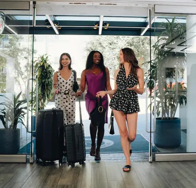 three women walking through a glass door with luggage at Montrose at Beverly Hills in Los Angeles