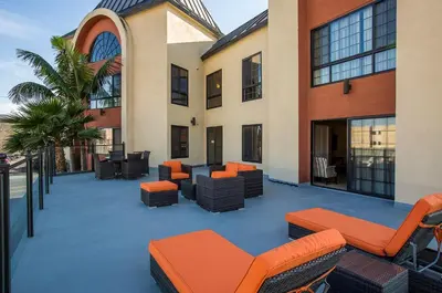 an outdoor patio with chairs and tables on a building at Coast Burbank Hotel in Burbank