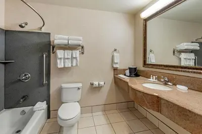 a bathroom with a toilet and a sink and a mirror at Citrus Suites Redlands Loma Linda Hotel in Redlands