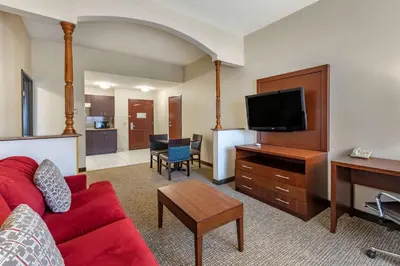 a living room with a red couch and a flat screen tv at Citrus Suites Redlands Loma Linda Hotel in Redlands