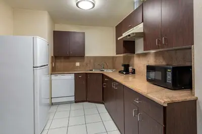 a kitchen with wooden cabinets and a white refrigerator at Citrus Suites Redlands Loma Linda Hotel in Redlands