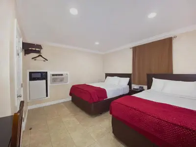 a hotel room with two beds with red sheets at Nite Inn at Universal City - Walking Distance to Universal Studios Hollywood in Los Angeles