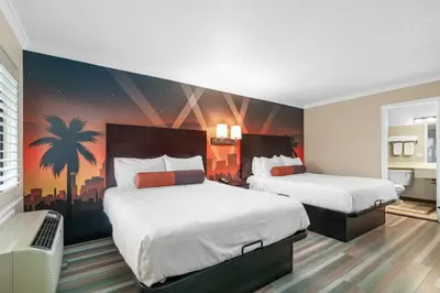 a bedroom with two beds and a palm tree mural at Santa Clarita Motel - Near six Flags Magic Mountain - Valencia in Santa Clarita