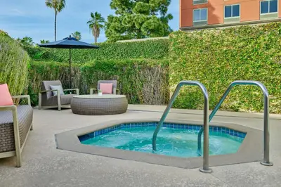 a hot tub in a patio with chairs and an umbrella at Courtyard Culver City Los Angeles in Los Angeles