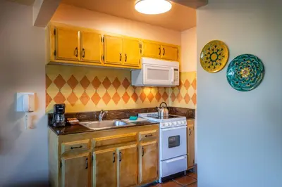 a kitchen with wooden cabinets and a sink and a stove at Hotel Pepper Tree Boutique Kitchen Studios - Anaheim in Anaheim