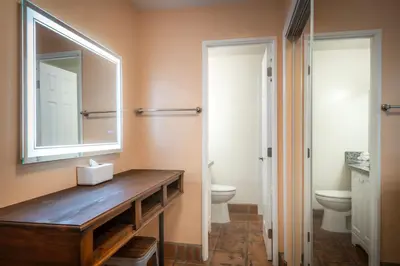 a bathroom with a sink and a mirror and a toilet at Hotel Pepper Tree Boutique Kitchen Studios - Anaheim in Anaheim