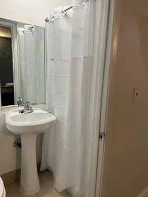 a bathroom with a sink and a white shower curtain at Budget Inn Hollywood in Los Angeles