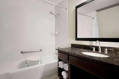 a bathroom with a sink and a tub and a mirror at Baymont by Wyndham Monterey Park in Monterey Park