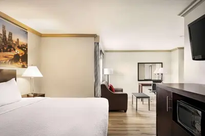 a hotel room with a bed and a chair at Baymont by Wyndham Monterey Park in Monterey Park