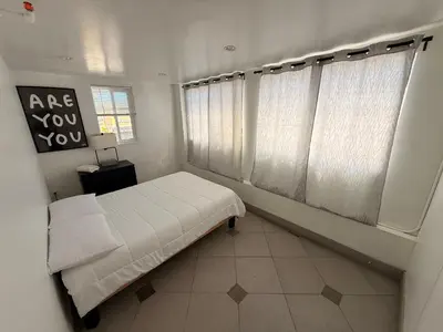 a bedroom with a bed with white sheets and windows at Culver City Hostel in Los Angeles