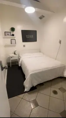 a bedroom with a large white bed with a sign on the wall at Culver City Hostel in Los Angeles