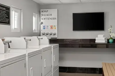 a bathroom with white counters and a flat screen tv at Peacock Suites in Anaheim