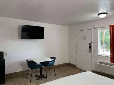a room with a table and a tv on the wall at Motel 6-Orange, CA - Anaheim in Anaheim