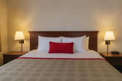 a bedroom with a large bed with a red pillow at Ramada by Wyndham Hawthorne/LAX in Hawthorne
