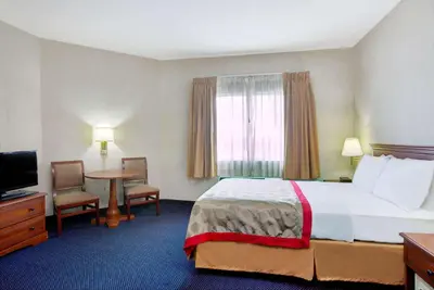 a hotel room with a large bed and a table at Ramada by Wyndham Hawthorne/LAX in Hawthorne