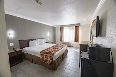a hotel room with a bed and a flat screen tv at Hospitality Inn in San Bernardino