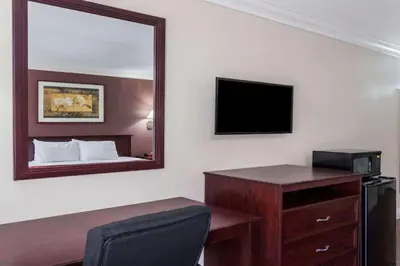 a hotel room with a desk and a mirror at Hospitality Inn in San Bernardino