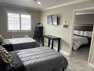 a bedroom with two beds and a table and a window at Cabana Inn & Suites in Long Beach