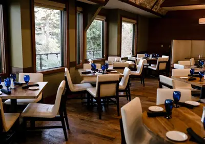 a dining room with tables and chairs and windows at Lake Arrowhead Resort & Spa in Lake Arrowhead