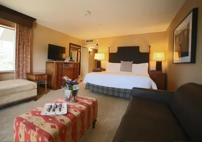 a hotel room with a bed and a living room at Lake Arrowhead Resort & Spa in Lake Arrowhead