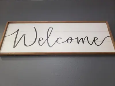 a sign that reads welcome hanging on a wall at Portofino Inn Burbank in Burbank