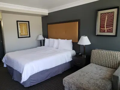 a hotel room with two beds and a chair at Portofino Inn Burbank in Burbank