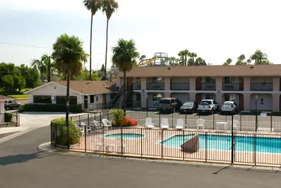 a pool in front of a hotel with palm trees at Colony Inn in Buena Park